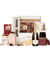 The Hamper Emporium A Touch<br>Of Luxury With... 750ML Pamper a lucky recipient with the finer things in life. This gorgeous hamper features a bottle of Chandon bubbles, a pair of stemless champagne flutes with 24-carat gold rims, a handpoured scented candle, a blush notebook, and a range of incredible gourmet nibbles for them to enjoy. What could be more luxurious?